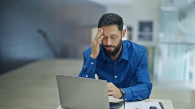 Genç İspanyol iş adamı ofiste çalışırken baş ağrısı çekiyor.