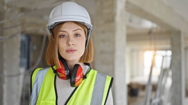 İnşaat alanında rahat bir ifadeyle duran genç sarışın mimar.