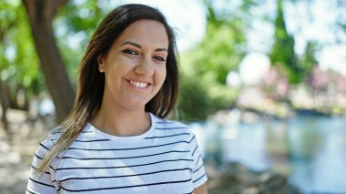 Ortadoğulu kadın parkta kendinden emin gülümsüyor.