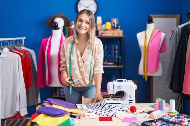 Young caucasian woman tailor cutting t shirt at sewing studio