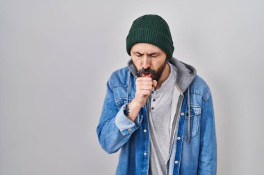 Yün şapka takan, kendini kötü hisseden ve soğuk algınlığı veya bronşitin belirtisi olarak öksüren Latin kökenli genç bir adam. sağlık hizmeti kavramı. 