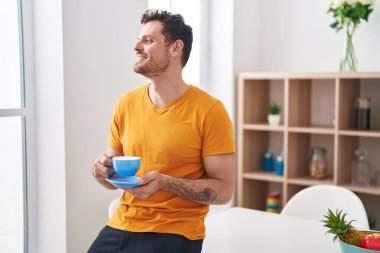 Genç İspanyol adam evde oturmuş kahve içiyor.