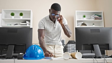 Afrika kökenli Amerikalı mimar ofisteki dokümanlarda akıllı telefon yazısıyla konuşuyor.