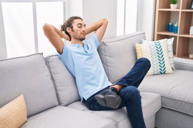 Genç İspanyol adam, ellerini başının üstüne koyup evinde kanepede oturarak rahatladı.