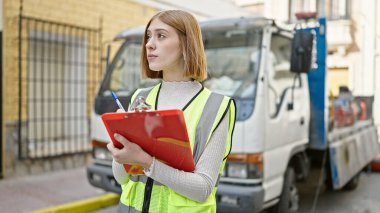 Sarışın bir kadın müteahhit sokakta yazı yazıyor.