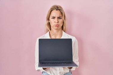 Genç, beyaz bir kadın dizüstü bilgisayar tutuyor. Depresyonda ve üzüntüden ağlıyor. Kızgın ve korkmuş. hüzünlü ifade. 