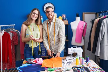 Erkek ve kadın terzi giyim fabrikasında defter üzerinde kumaş kesiyor.