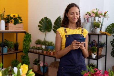 Young african american woman florist smiling confident using smartphone at flower shop