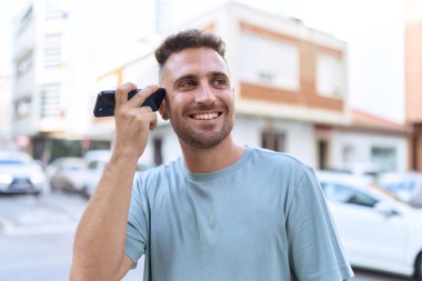 Genç İspanyol adam gülümsüyor. Caddedeki akıllı telefondan kendine güvenen bir sesli mesaj dinliyor.