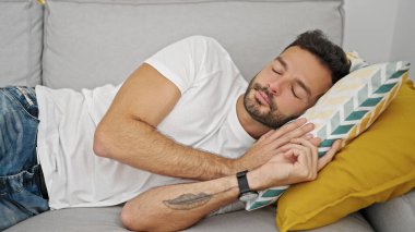 Genç İspanyol adam kanepede uzanıp evde uyuyor.