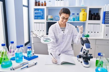 Genç ve güzel İspanyol bilim kadını. Laboratuvarda not defterine numune tutuyor.