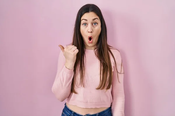 Young Brunette Woman Standing Pink Background Surprised Pointing Hand Finger — Foto Stock