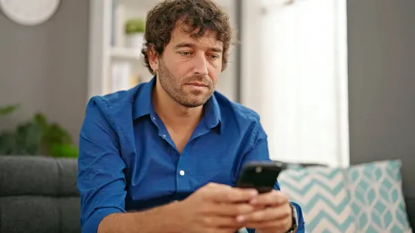 Νεαρός Ισπανόφωνος Άντρας Που Χρησιμοποιεί Smartphone Κάθεται Στον Καναπέ Στο — Φωτογραφία Αρχείου