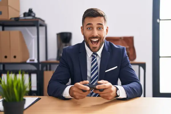 オフィスでビデオゲームをしているハンサムなヒスパニックの男は笑って 面白いクレイジーな冗談のために大声で笑います — ストック写真