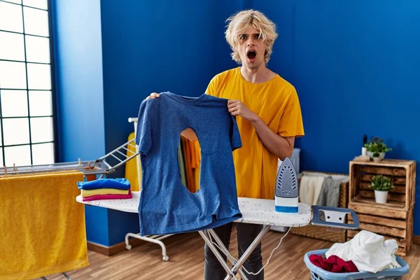 Çamaşır Odasında Yanık Delikli Tişört Tutan Genç Sarışın Adam — Stok fotoğraf