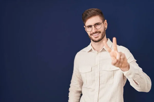Hispánec Vousy Stojící Nad Modrým Pozadím Usmívající Kameru Ukazující Prsty — Stock fotografie