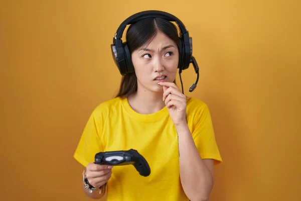 中国年轻女子玩电子游戏时牵着控制器 牵着手思考着一个问题 牵着下巴忧心忡忡 — 图库照片