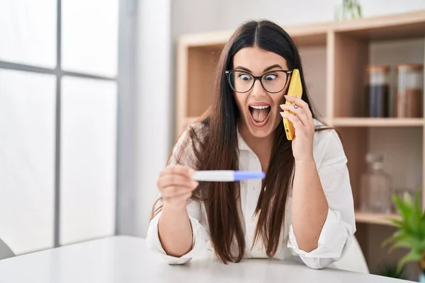 Elinde Hamilelik Testi Olan Genç Esmer Kadın Telefonda Konuşuyor Çılgınlığı — Stok fotoğraf