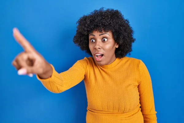 Black Woman Curly Hair Standing Blue Background Pointing Finger Surprised — Stock Photo, Image