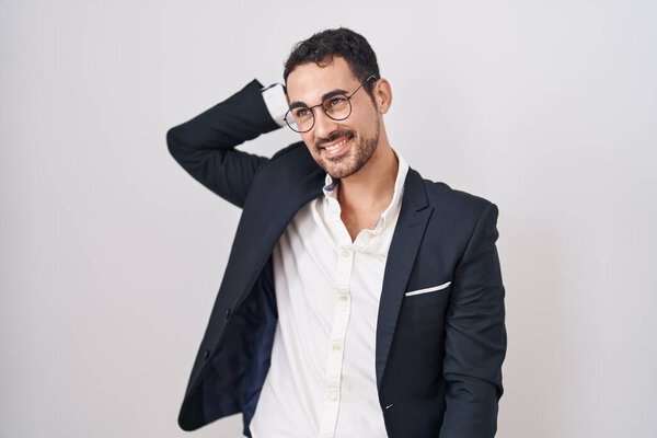 Handsome business hispanic man standing over white background smiling confident touching hair with hand up gesture, posing attractive and fashionable 