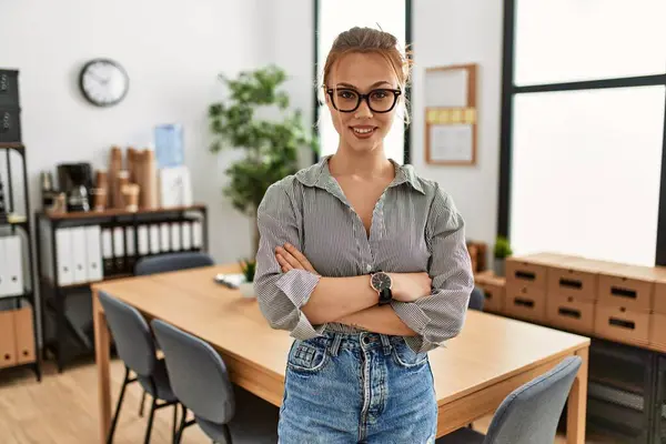 Beyaz kadın iş kadını gülümseyen, kendine güvenen, kollarını kavuşturup ofiste el kol kola duran.
