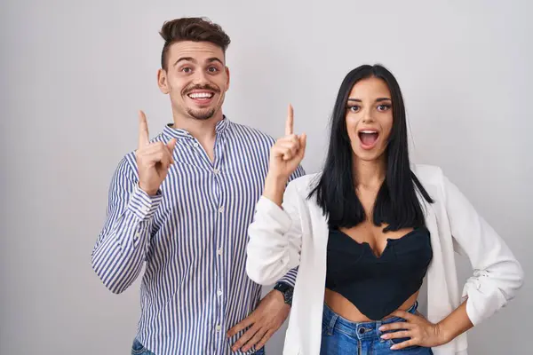 若いヒスパニック系のカップルが成功したアイデアで指を指して白い背景の上に立っている 興奮して幸せよ 第1位 — ストック写真