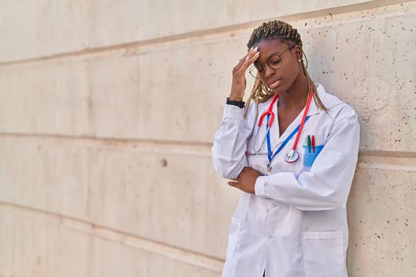 African american woman doctor stressed leaning on wall at hospital