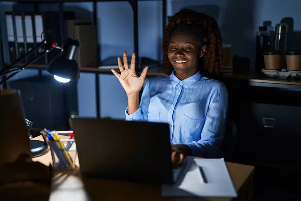 夜にオフィスで働くアフリカ人女性が自信と幸せを笑いながら指ナンバー5を指さして指を指さす — ストック写真