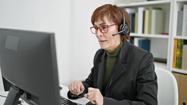 Mature hispanic woman university teacher using computer and headset at library university