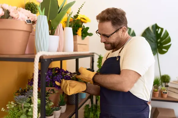 Middle age man florist cutting plants at flower shop