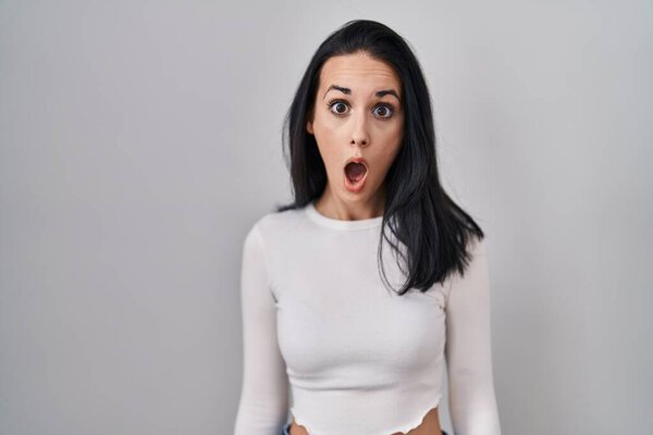 Hispanic woman standing over isolated background afraid and shocked with surprise expression, fear and excited face. 