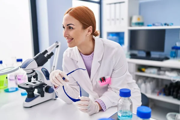 Young caucasian woman scientist smiling confident holding security glasses at laboratory