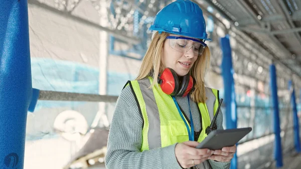 Young blonde woman builder smiling confident using touchpad at street