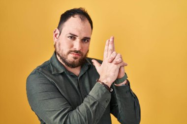 Ayrıca sarı arka planda sakallı İspanyol bir adam. Elinde sembolik bir silah var. El hareketleriyle cinayet silahlarıyla oynuyor. 