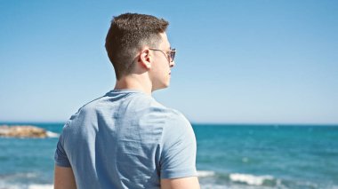 Genç İspanyol turist deniz kenarında dikiliyor.