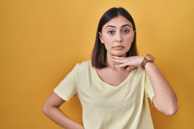 Sarı arka plan üzerine günlük tişört giyen İspanyol kız boğazını bıçak niyetine kesiyor, saldırganlığı şiddetle tehdit ediyor. 