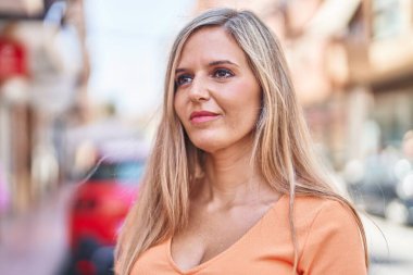 Sokakta ciddi bir ifadeyle duran genç sarışın kadın.