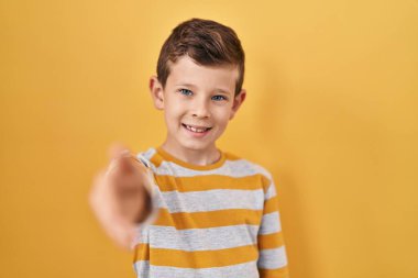 Sarı arka planda duran beyaz bir genç dostça bir selamlama ve hoş geldin hediyesi olarak el sıkışır. başarılı iş. 