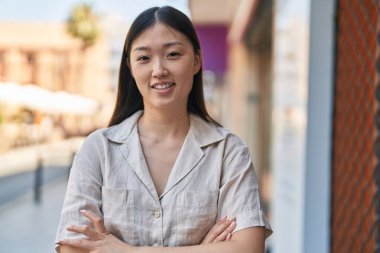 Çinli kadın kendine güveni tam caddede kollarını kavuşturmuş duruyor.