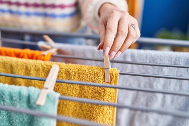 Çamaşır odasında çamaşır ipine elbise asan beyaz bir kadın.