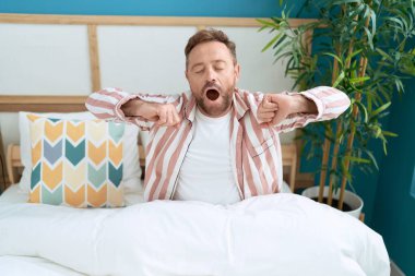 Middle age man waking up stretching arms at bedroom