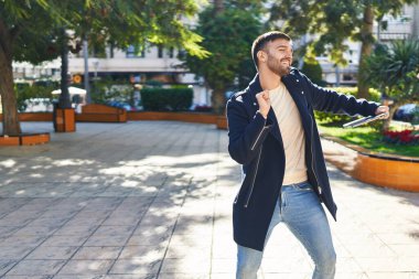 Genç İspanyol adam parkta dizüstü bilgisayar tutuyor.