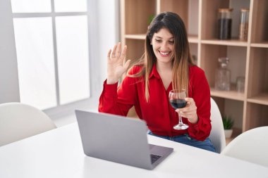 Genç esmer kadın video çekiyor. Kırmızı şarap içiyor. Pozitif ve mutlu görünüyor. 