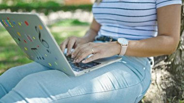 Parkta dizüstü bilgisayar kullanan Ortadoğulu bir kadın.