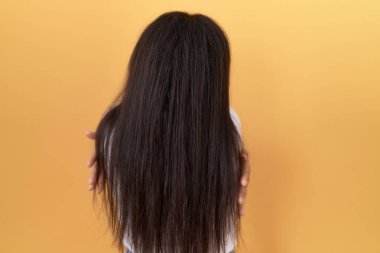 Sarı arka plan üzerine günlük beyaz t-shirt giyen genç bir Arap kadın mutlu ve pozitif bir şekilde sarılıyor. Sevgi ve özgüven. 