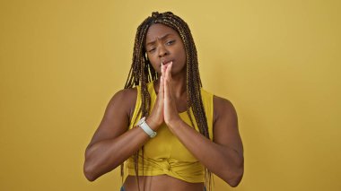 Afrikalı Amerikalı bir kadın izole edilmiş sarı arka plan için dua ediyor.