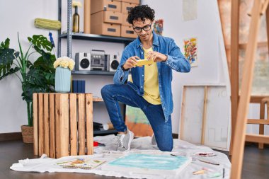 Genç İspanyol ressam resim çizmek için resim stüdyosunda akıllı telefon kullanıyor.