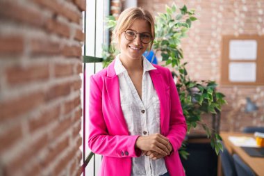 Ofiste kendine gülen genç sarışın iş kadını.