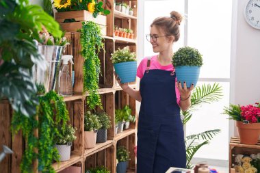 Çiçekçide çiçekleri tutan, kendine güvenen genç sarışın kadın.