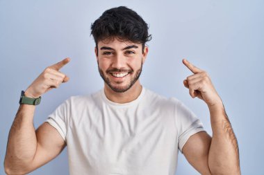 Beyaz arka planda sakallı İspanyol bir adam gülümseyerek iki eliyle kafasını işaret ediyor. Harika bir fikir ya da düşünce, iyi bir hafıza. 